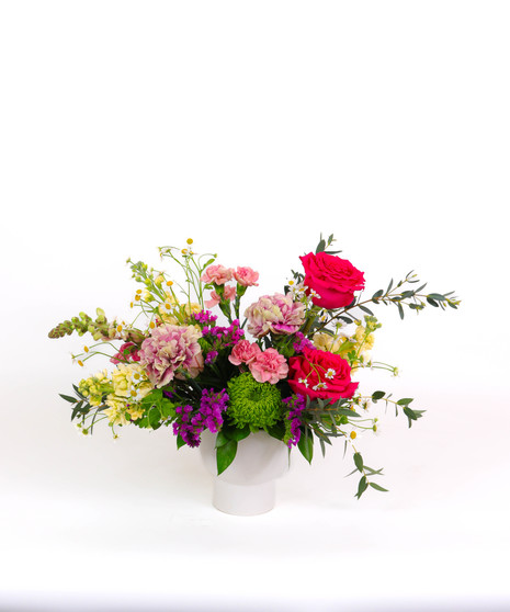 Berry Bliss floral arrangement with raspberry roses, lisianthus, chamomile daisies, and greenery in a white ceramic vase