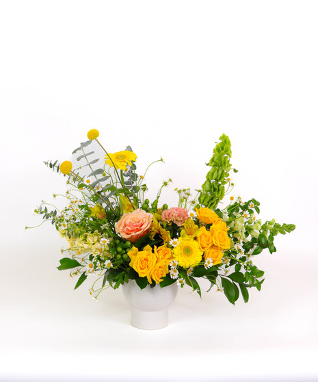 Sunset Cliffs floral arrangement with yellow and peach roses, craspedia, and golden mums in a white ceramic vase