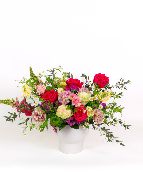 Berry Bliss floral arrangement with raspberry roses, lisianthus, chamomile daisies, and greenery in a white ceramic vase