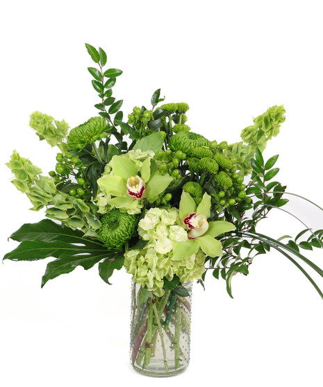 Luck of the Irish floral arrangement with green orchids, hydrangeas, bells of Ireland, and mums in a clear hobnail glass vase